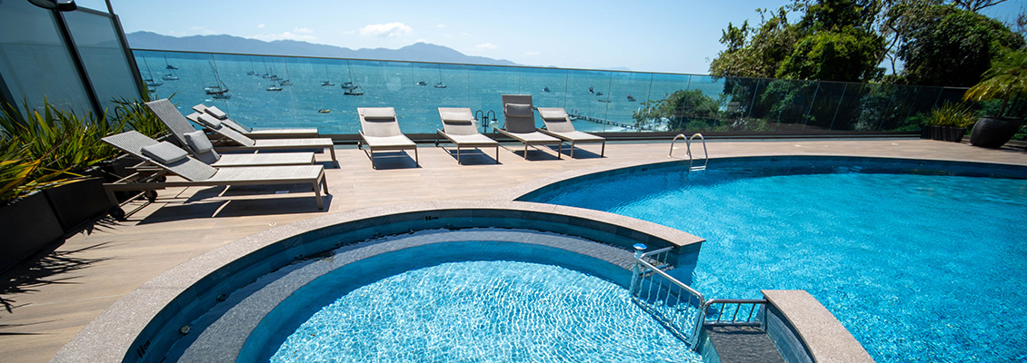 Piscina com vista para o mar, espreguiçadeiras ao redor, cenário de descanso e lazer em uma área externa de luxo, ideal para relaxar