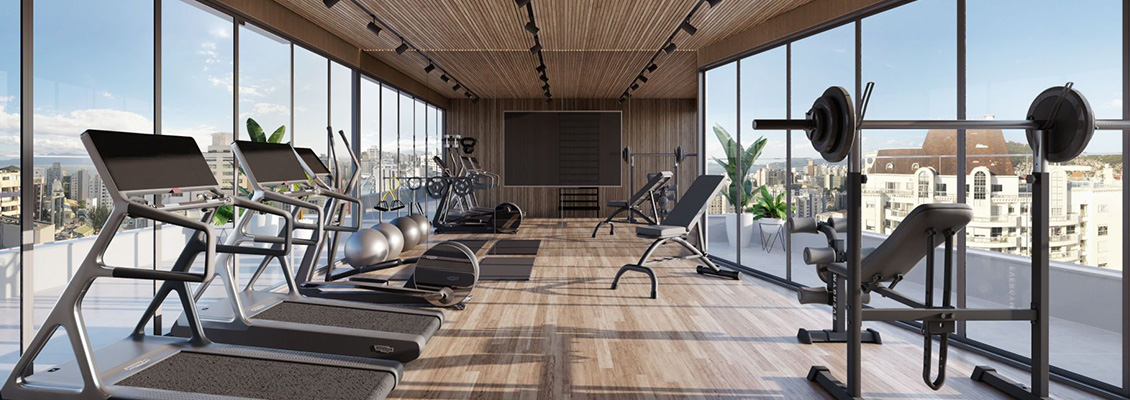 Academia com esteiras, bicicletas ergométricas, halteres e barra de musculação, piso de madeira e grandes janelas panorâmicas com vista da cidade em um empreendimento de alto padrão ACCR.